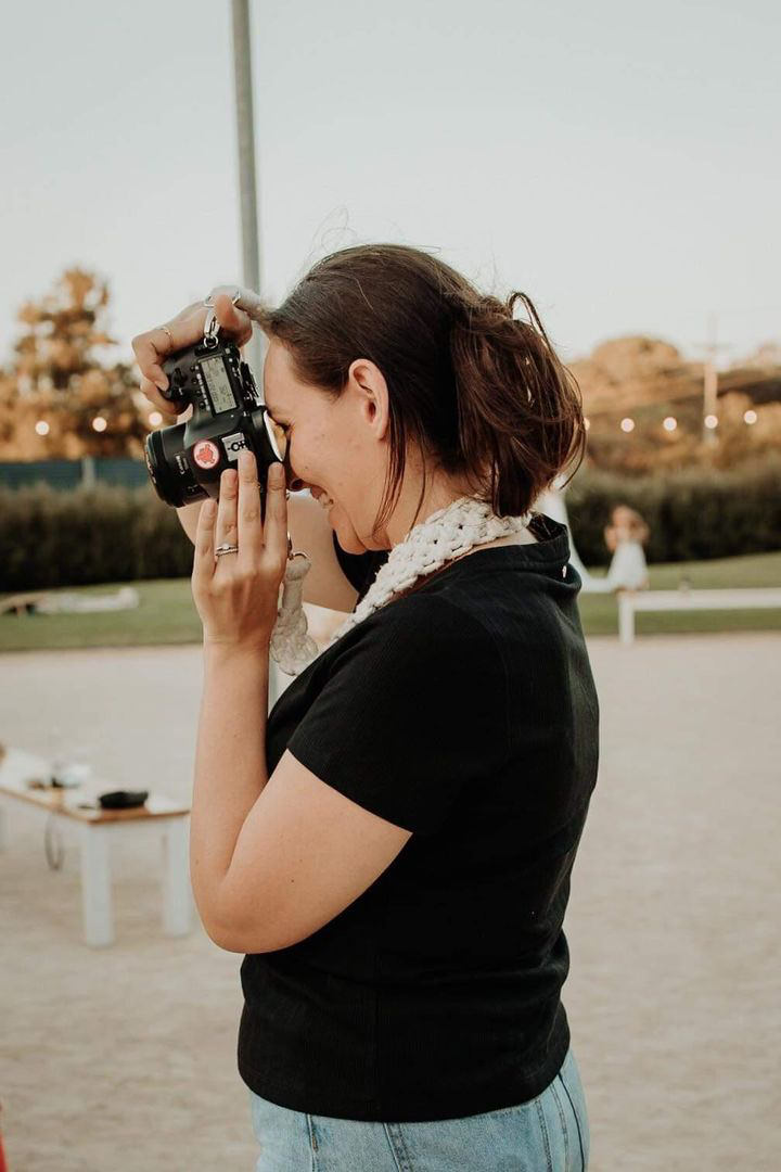 Photographer-smiling-as-she-holds-camera-to-her-face-and-takes-a-photo