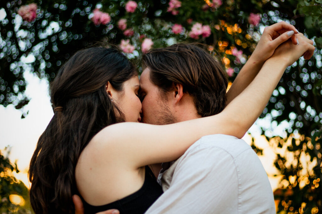 Closeup-of-couple-almost-kissing-in-front-of-tree-with-pink-flowers-in-the-background