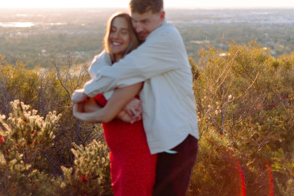 Blurry-shot-of-couple-all-wrapped-up-in-each-others-arms-and-laughing-bushes-behind-them-in-focus