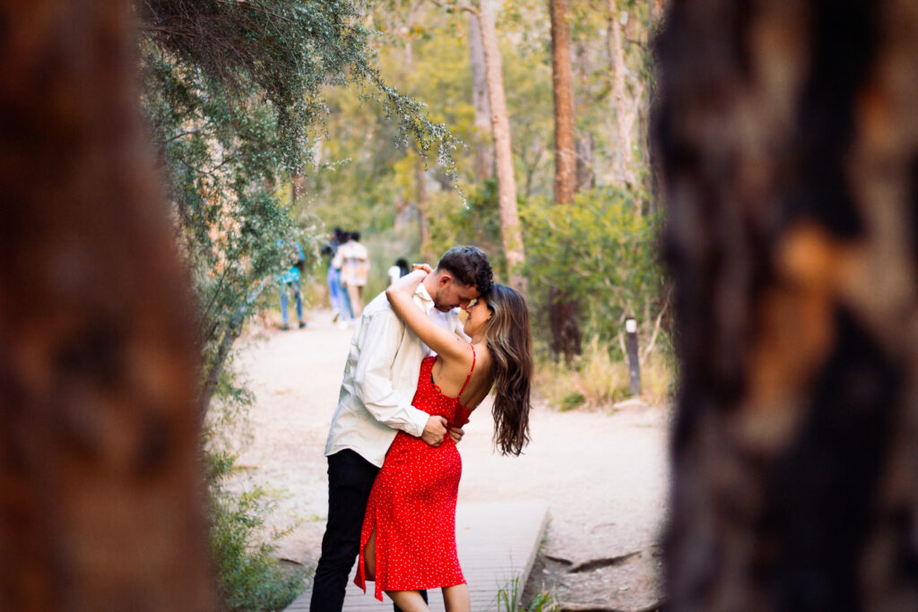 Couple-almost-kissing-in-bush-clearing-man-holding-womans-waist-with-her-arms-around-his-neck